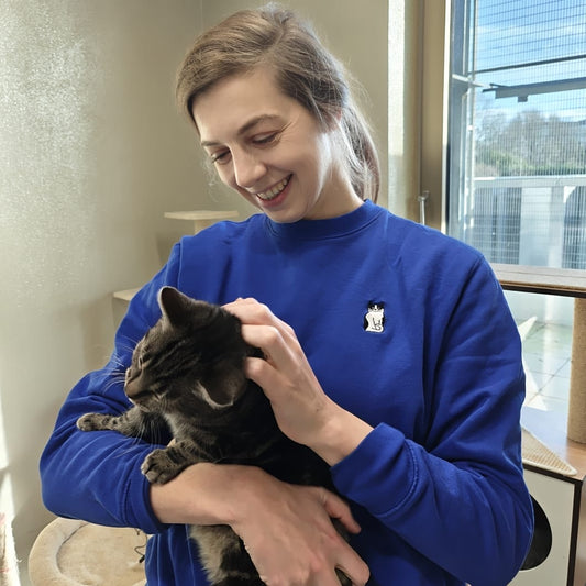 Stijlvolle blauwe trui met zwart-witte tuxedo kat, duurzaam geproduceerd, met tabby kat op afbeelding