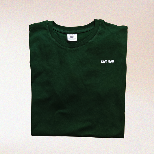 Donkergroene t-shirt met opschrift ‘Cat Dad’, tegen roze achtergrond
