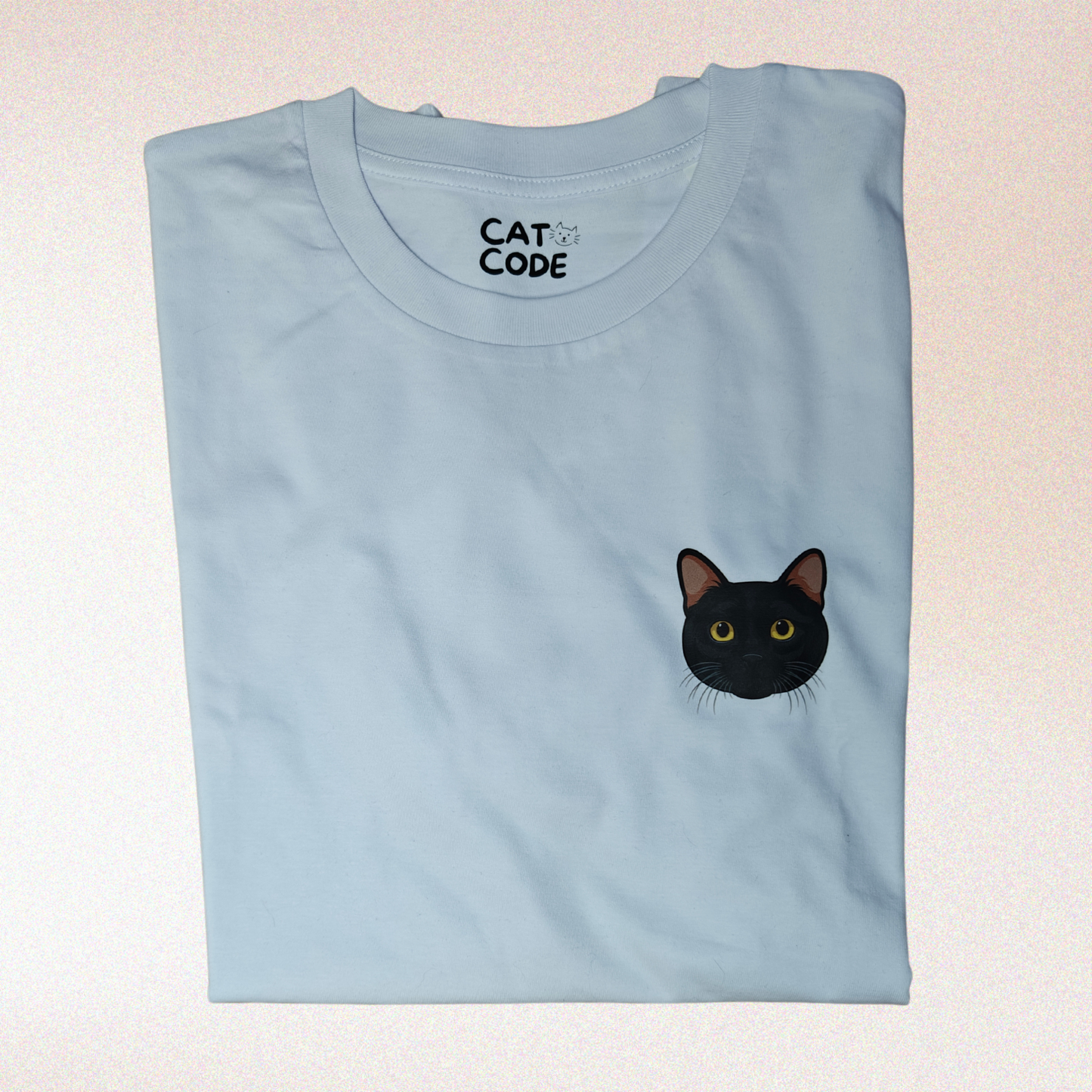 Witte t-shirt met zwart kattengezicht, tegen roze achtergrond.
