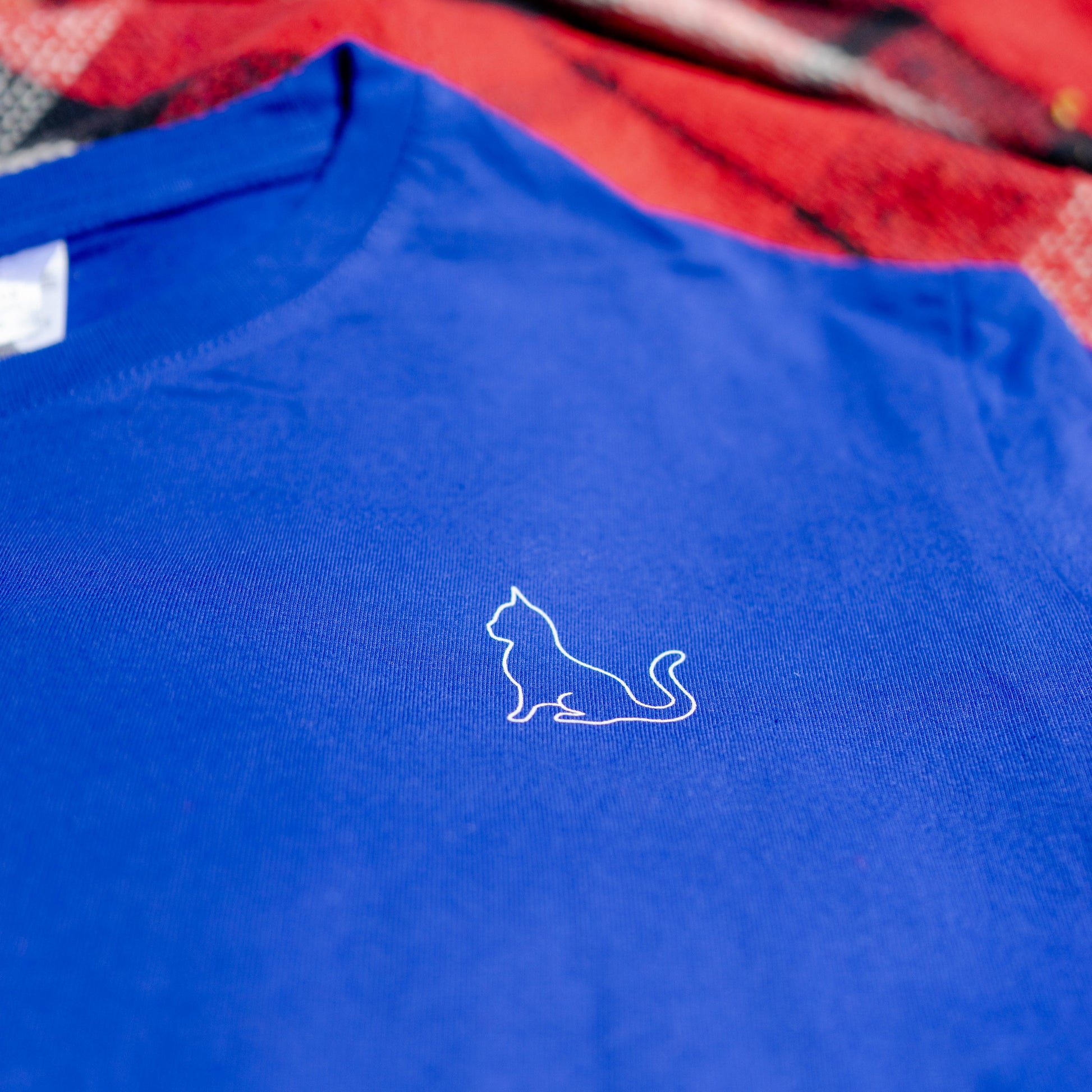 Detailfoto van blauwe katoenen T-shirt met kleine kat in lijntekening op de borst