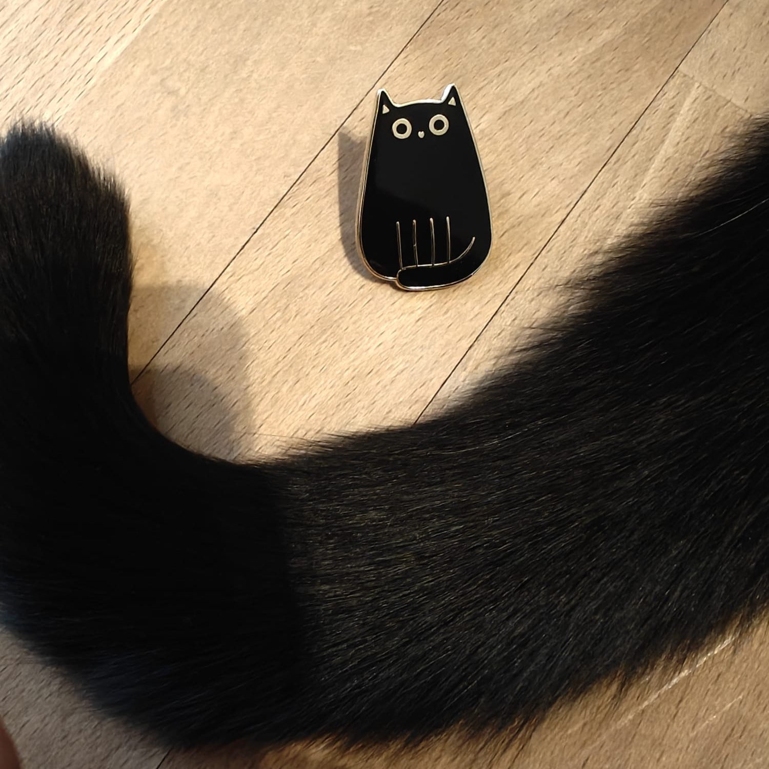 Kleine enamel pin in de vorm van een zwarte kat met verfijnde gouden details – subtiel en elegant