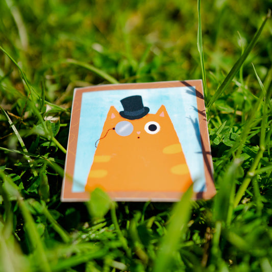 Sticker met een rosse kat met hoedje op en een monocle bril aan, voor de echte kattenliefhebber.
